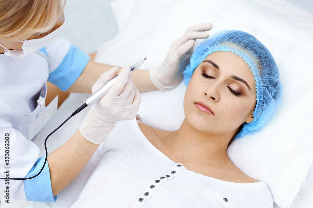 Professional beautician doing eyebrow tattoo at woman face. Permanent brow makeup in beauty salon, closeup. Cosmetology treatment Professional beautician doing eyebrow tattoo at woman face. Permanent brow makeup in beauty salon, closeup. Cosmetology treatment