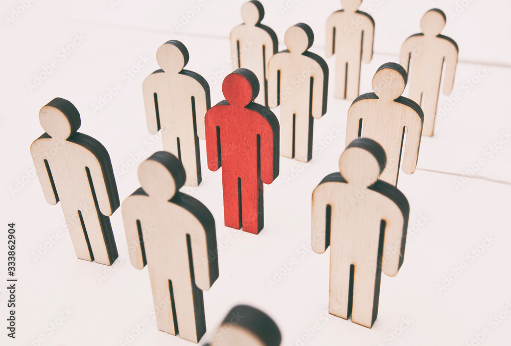 Many wooden persons on the table and one person is painted in red color. The concept of coronavirus or another virus is spreading to people. Many wooden persons on the table and one person is painted in red color. The concept of coronavirus or another virus is spreading to people.
