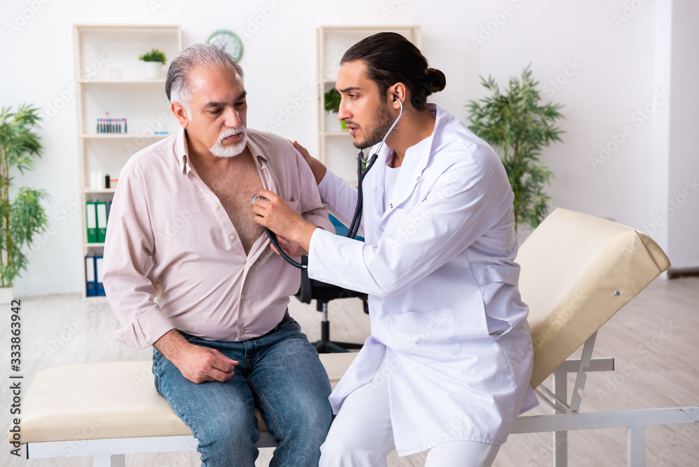 Obraz premium Old man visiting young male doctor cardiologist