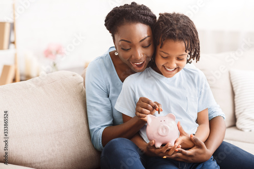 Φωτογραφία African american family inserting money into piggybank