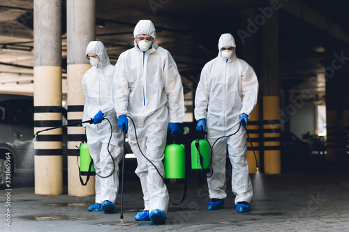 Workers in coronavirus suits cleaning streets with chemicals © Prostock-studio