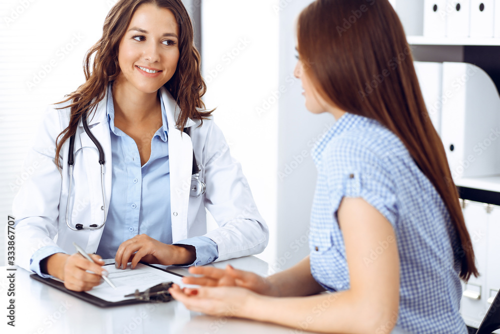 Doctor and patient talking while sitting at the desk. The physician discussing healthy lifestyle. Health care, medicine and patient service concept Doctor and patient talking while sitting at the desk. The physician discussing healthy lifestyle. Health care, medicine and patient service concept