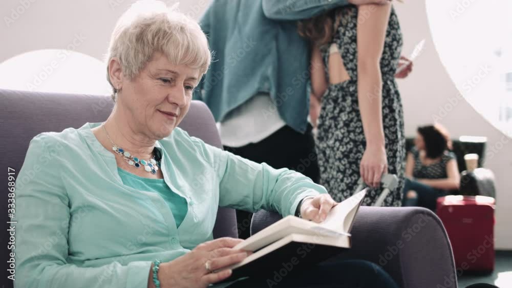 Senior adult woman reading book in airport waiting lounge Senior adult woman reading book in airport waiting lounge