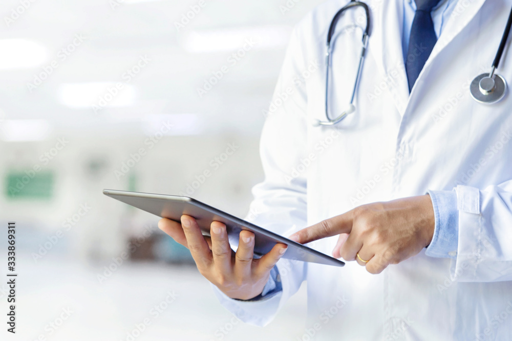 Male doctor using his digital tablet in the consultation.Medicine and healthcare concept Male doctor using his digital tablet in the consultation.Medicine and healthcare concept