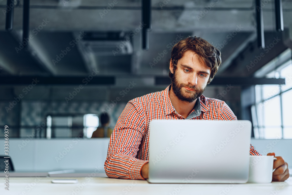 Puzzled thoughtful businessman sitting at his working table in an office. Business concept Puzzled thoughtful businessman sitting at his working table in an office. Business concept