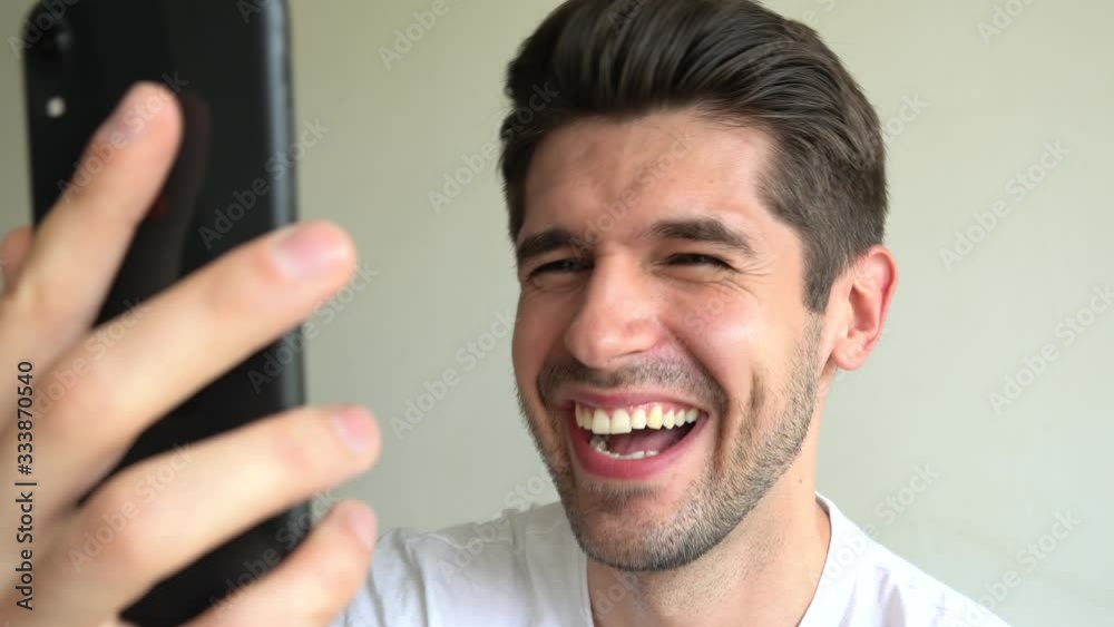 Close up of a young attractive guy laughing on the funny video on his phone without a stop isolated Close up of a young attractive guy laughing on the funny video on his phone without a stop isolated