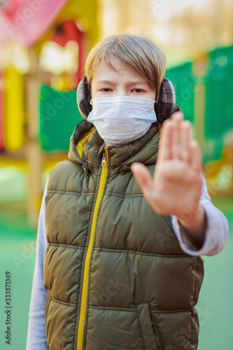 School boy wearing medical mask, showing stop sign photo