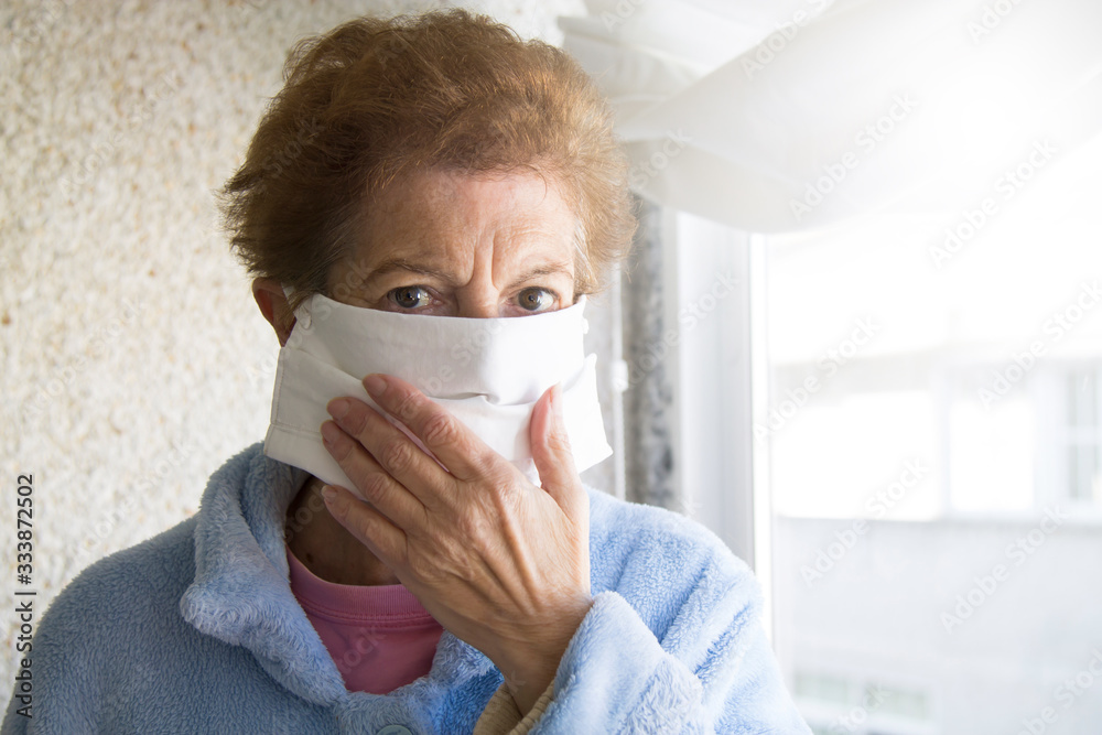 Portrait of senior woman putting on medical mask in nursing home. Safety in public places during outbreak of coronavirus. Portrait of senior woman putting on medical mask in nursing home. Safety in public places during outbreak of coronavirus.