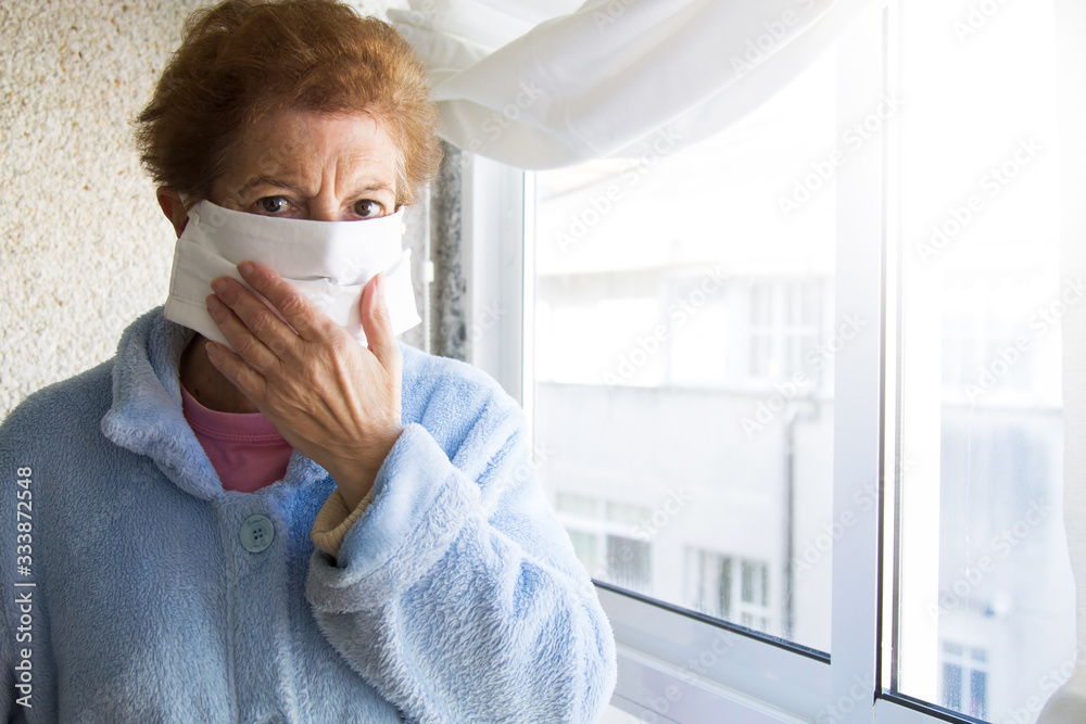 Portrait of senior woman putting on medical mask in nursing home. Safety in public places during outbreak of coronavirus. Portrait of senior woman putting on medical mask in nursing home. Safety in public places during outbreak of coronavirus.