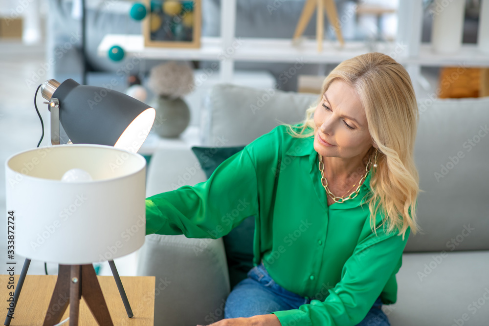 Blonde woman in a green blouse looking busy choosing furniture Blonde woman in a green blouse looking busy choosing furniture