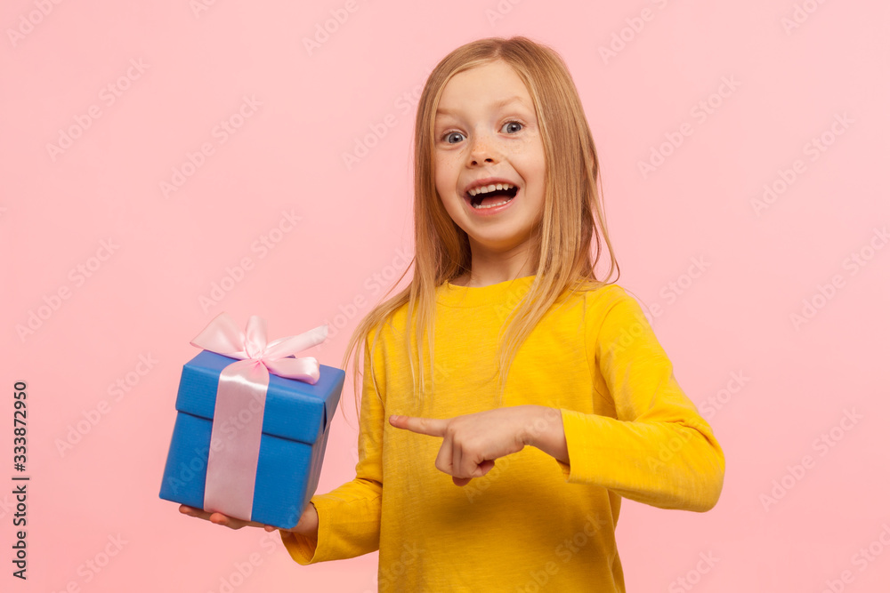 Portrait of delighted amazed little girl pointing gift box, boasting present and looking with astonishment to camera, shocked by birthday surprise. indoor studio shot isolated on pink background Portrait of delighted amazed little girl pointing gift box, boasting present and looking with astonishment to camera, shocked by birthday surprise. indoor studio shot isolated on pink background