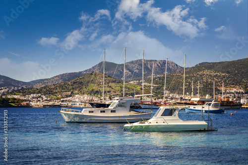 Beautiful landscape. Sea shore with clear transparent water and boats on the background of mountains and the city. Bodrum, Turkey, Mediterranean Sea. A popular travel destination.