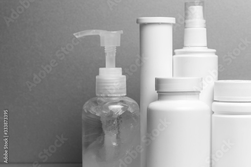 5 containers without inscriptions for medicines, vitamins, sprays, antiseptic gel stand on a gray shelf. layout for the design of the pharmacy and the store. monochrome
