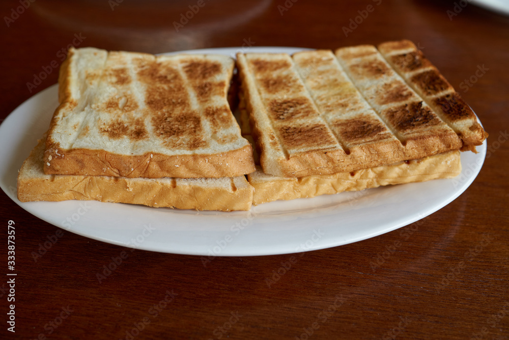 Breakfast сrispy fried toasts on a white plate on a wooden table. Breakfast сrispy fried toasts on a white plate on a wooden table.