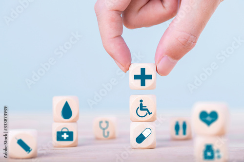 Hand chooses a emoticon icons healthcare medical symbol on wooden block , Healthcare and medical Insurance concept