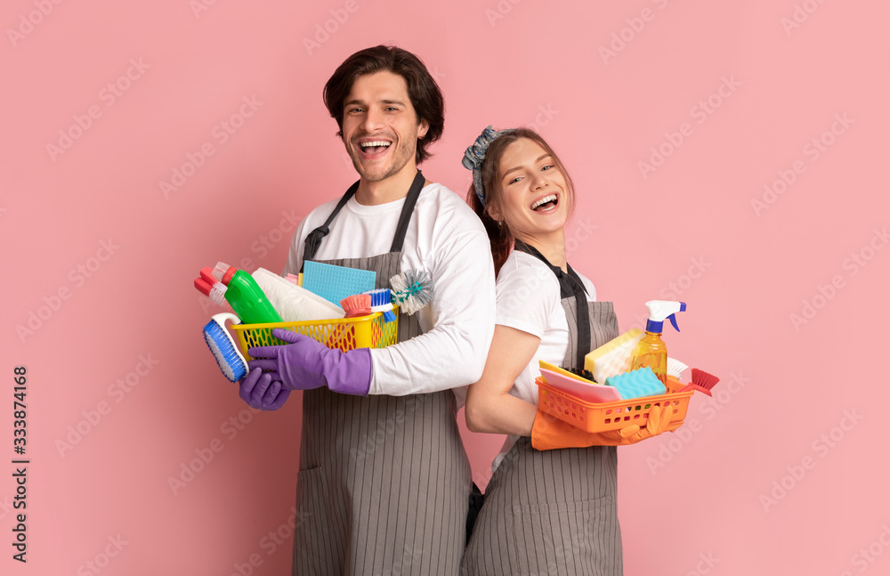 Team of janitors with cleaning supplies on pink background Team of janitors with cleaning supplies on pink background