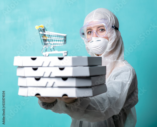 pizza delivery girl with boxes in protective suit with boxes and shopping cart