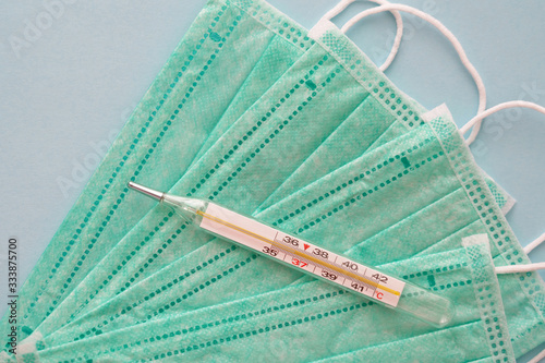 Body hydrargyric glass thermometer with 36.6 temperature on medical masks, anti-infective hygienic and health protection concept, Coronavirus Covid-19 prevention photo