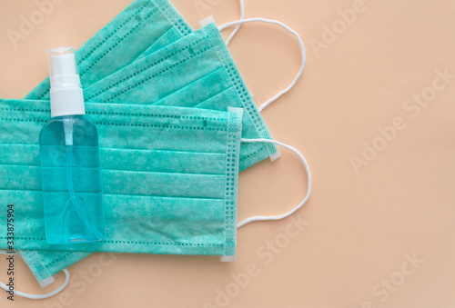 Medical masks and hand sanitizer blue bottle on pink background, anti-infective hygienic and health protection concept, Coronavirus Covid-19 protection photo