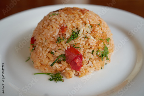 Spicy fried rice with vegetables on a white plate, dinner in a restaurant. 