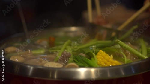 Slow motion move of hot pot steam boiling marking with friend and family using chopsticks to share with others. Healthy organic authentic traiditional vegetables soup with exotic sauces for vegetarian photo