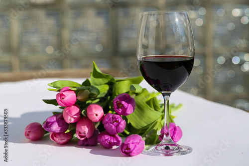 a bouquet of tulips with a glass of wine on a garden table