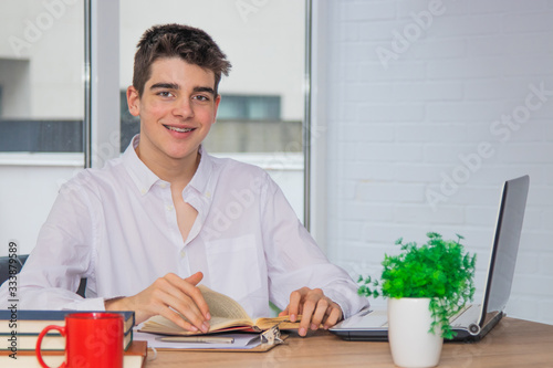 young student teenager at home or college desk with books and computer