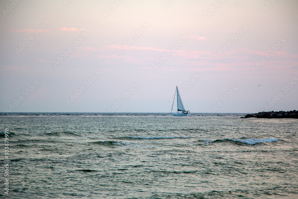sailboat on ocean with sunset sky background