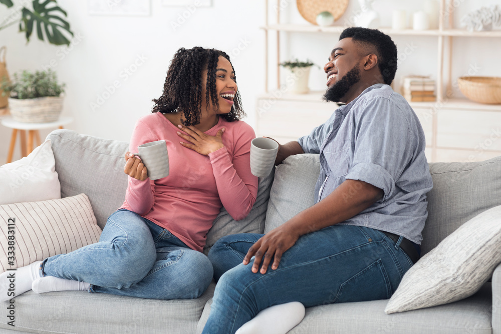 Joyful Black Couple Relaxing On Couch With Coffee, Sitting At Home Joyful Black Couple Relaxing On Couch With Coffee, Sitting At Home