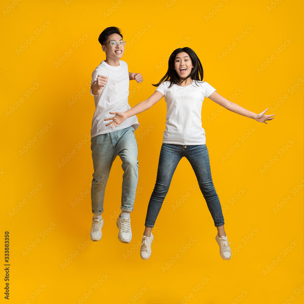 Fototapeta premium Carefree young asian couple posing over yellow background