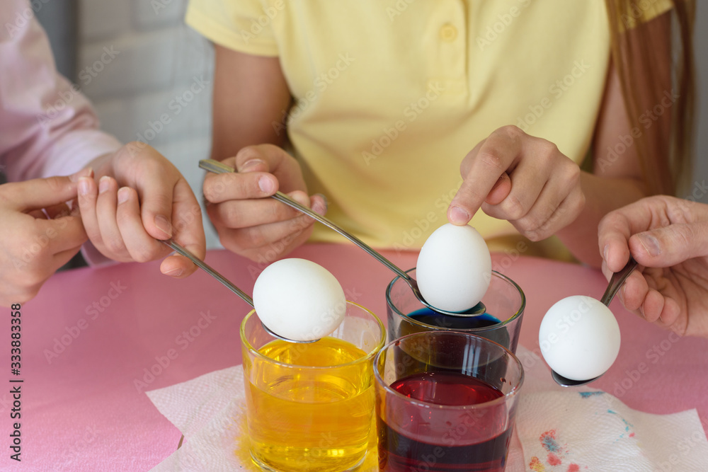 Hands dip chicken eggs in a dye solution Hands dip chicken eggs in a dye solution
