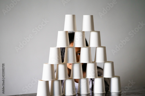 Kids Playing with white paper cups building a cup tower on the table.  Sisters, siblings playing together. photo