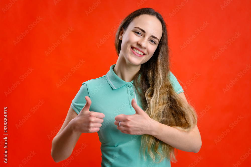 Portrait of a young beautiful girl on a red background. A model with long hair is talking to the camera, showing hands. Portrait of a young beautiful girl on a red background. A model with long hair is talking to the camera, showing hands.