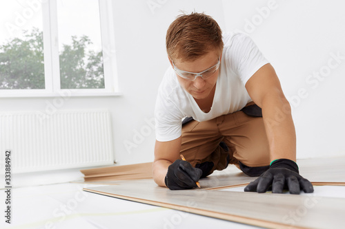 Master lays a wooden floor in apartment. Repair in the apartment. Installing light laminate floor with substrate under a laminate on white background