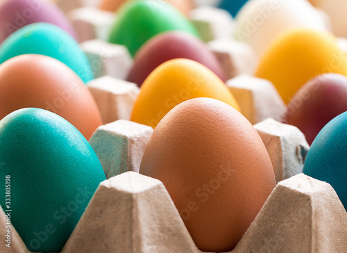 Different colorful Easter eggs in the cardboard egg tray. Easter decoration. Selective focus.  photo