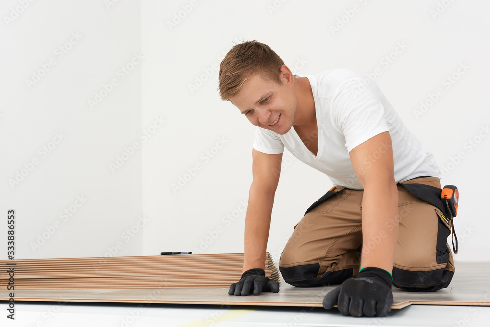 Male worker installing laminate flooring. Adult man lays the laminate panel on the substrate with the technology Male worker installing laminate flooring. Adult man lays the laminate panel on the substrate with the technology