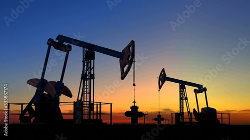 Two oil pump jacks extracting crude oil under beautiful sunset sky. Extracting fossil oil is one of the cheapest and effective methods of power generation among non renewable energy sources. Loopable.
