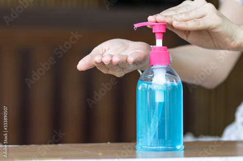 Female hands using wash hand sanitizer gel pump dispenser. alcohol antiseptic gel,prevent against infection of Covid-19 outbreak,avoid contaminating with Corona virus,anti-bacteria . copy space. selec photo