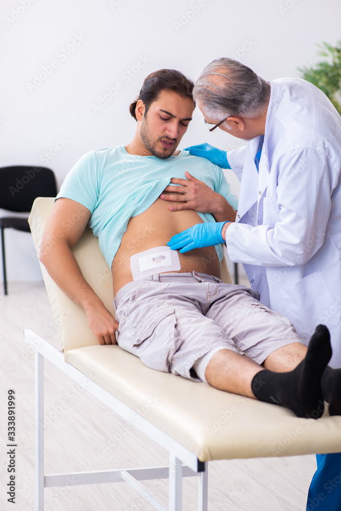 Injured young man visiting experienced male doctor Injured young man visiting experienced male doctor