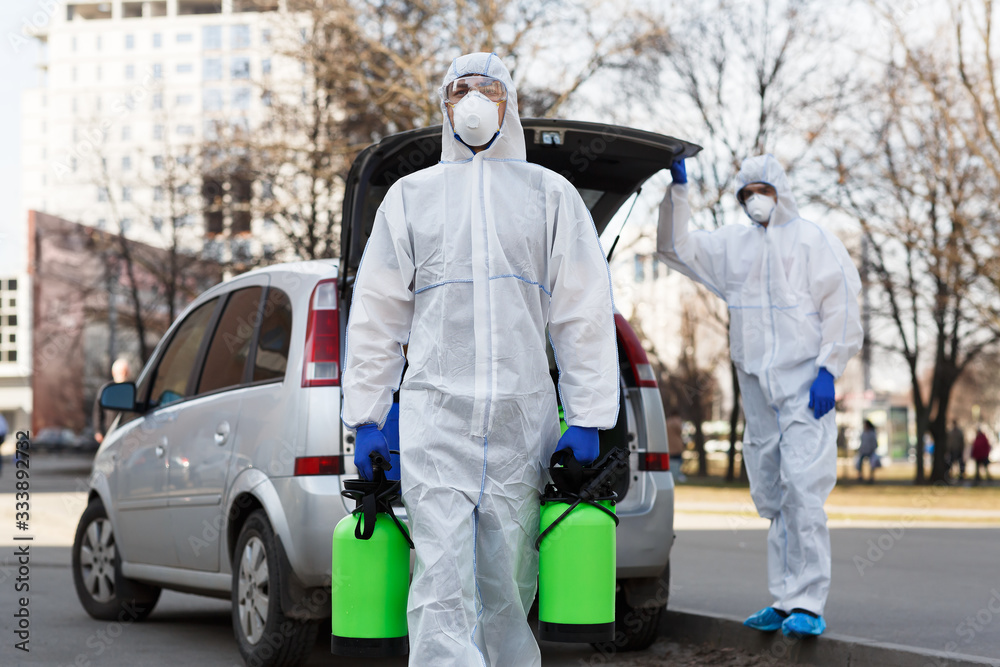 Man in coronavirus hazmat suit carrying disinfection gas