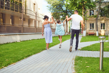 Happy family walking together in the street of the city