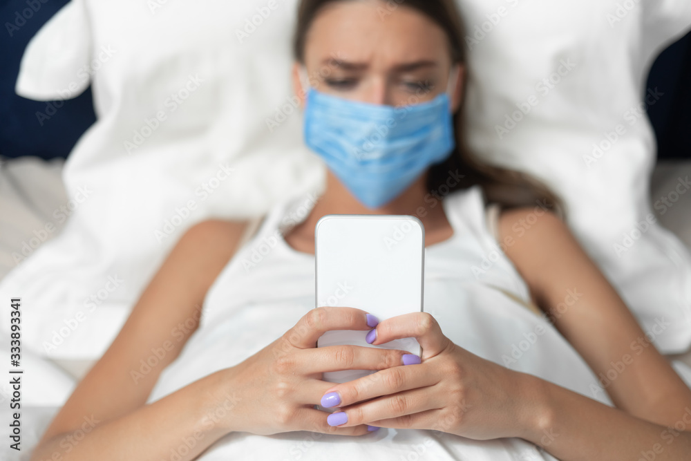 Girl In Mask Using Smartphone Lying In Bed At Home Girl In Mask Using Smartphone Lying In Bed At Home