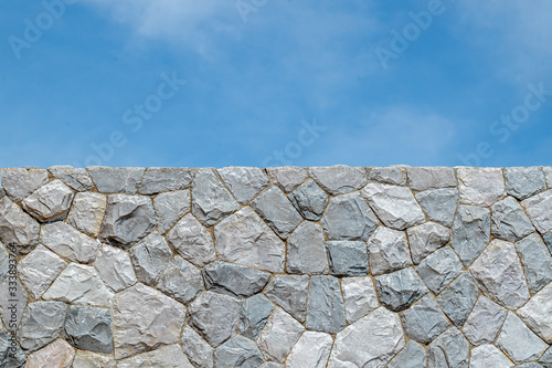 Stone wall background texture under blue sky on sunshine day.