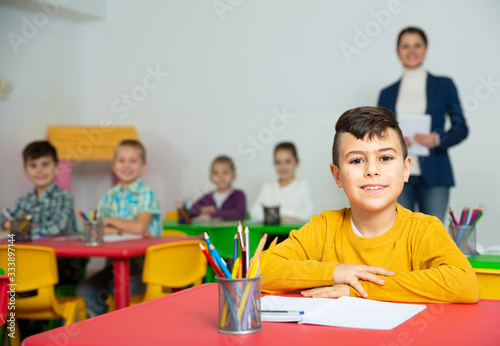 Smiling Hispanic schoolboy at school desk