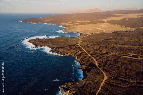 Aerial view of lava cliffs and ocean with warm sunset. Lanzarote, Canary Islands.