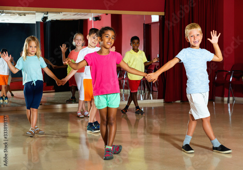 Smiling children primary school trying dancing salsa dance in modern studio