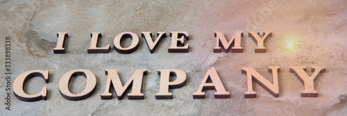 I love my company , writen wooden letters on stone background