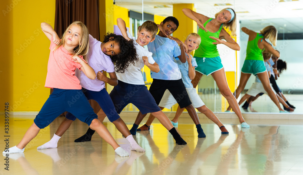 Cheerful little children studying modern style dance in class