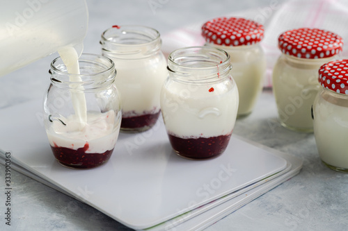Canvas Print Filling glass jars with a milk mixture to produce homemade yoghurt