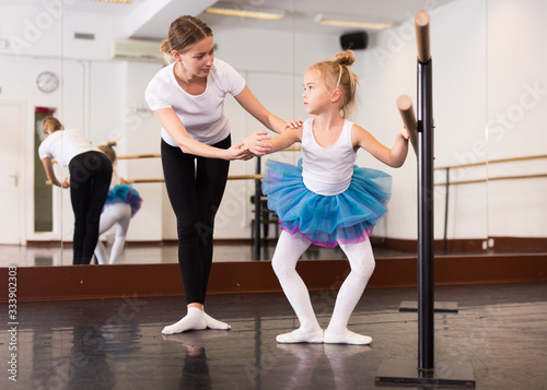 Trainer teaching little ballerina